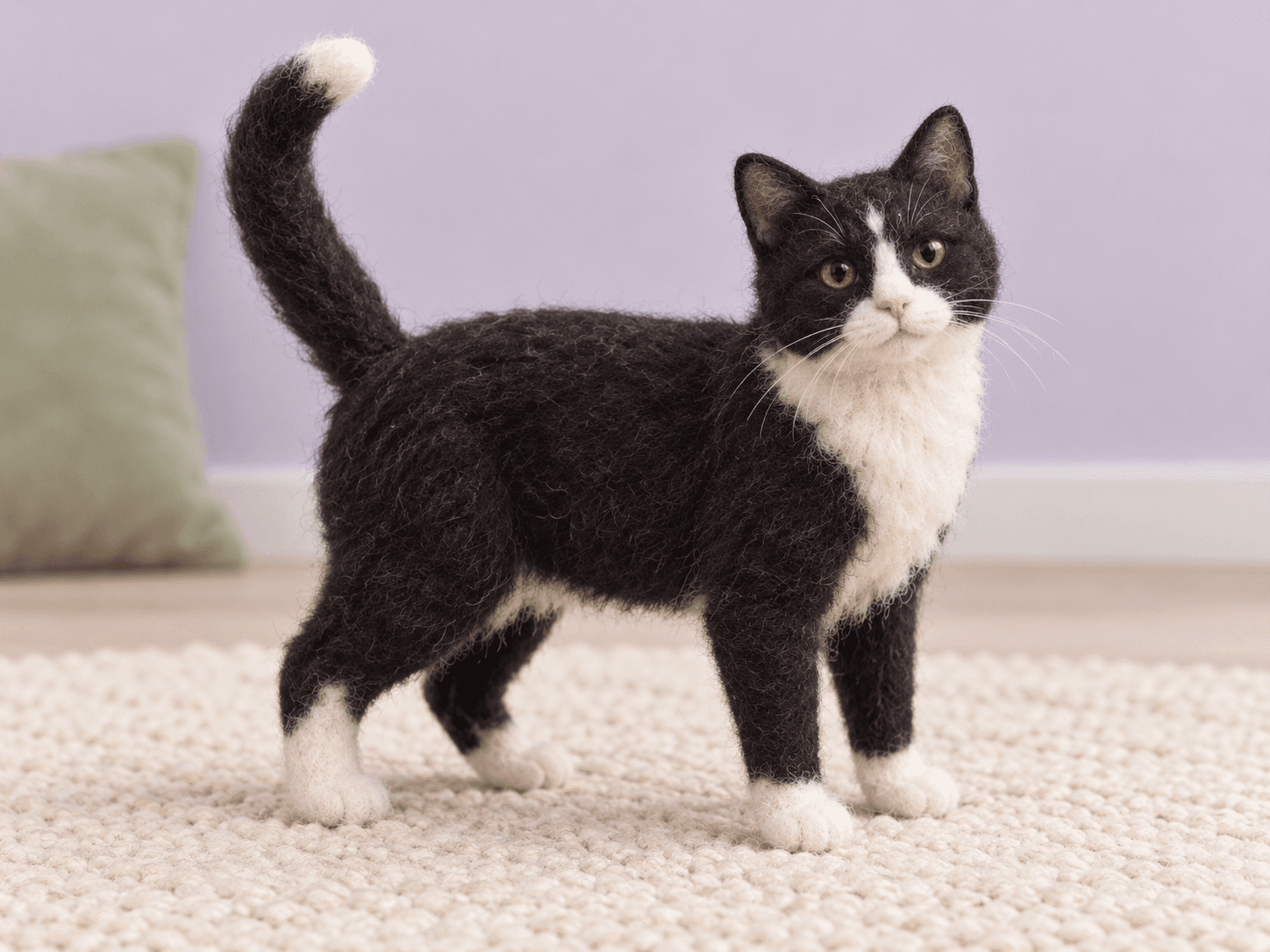 A relaxed tuxedo cat with an upright tail in a soft lavender setting
