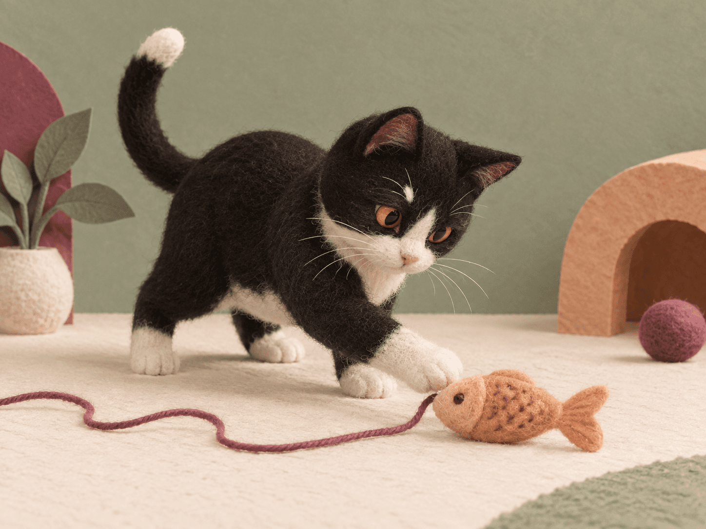A playful felt cat exploring a toy